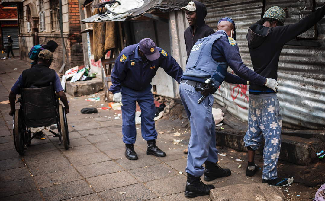 Police in Gauteng search street people in a area used by the homeless during the national lockdown